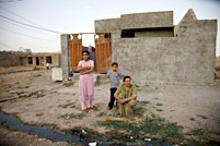 A family makes a new broom outside of their home at the Azadi IDP Camp in Iraq.