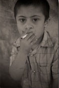 A six year old boy smokes cigarettes in the Moqoble Refugee Camp for Syrian Kurds in Iraq