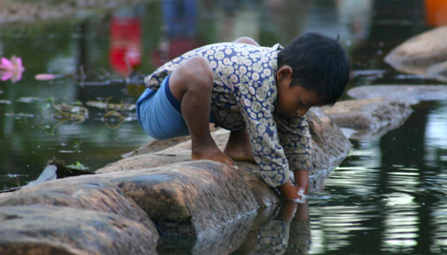 A boy plays in the water outside of the temple in Angkor Wat