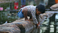  boy plays in the water outside of the temple in Angkor Wat