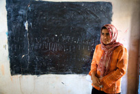 Tara Saifulla, 17, stands next to what was once a classroom's chalkboard.